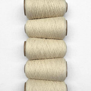 Five cones of natural thin wool yarn laying in flat lay side-by-side vertically on white background