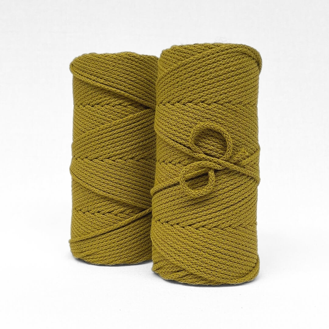 two rolls of braided cotton cord in colour-way chartreuse stnading side by side on slight angle with white back drop