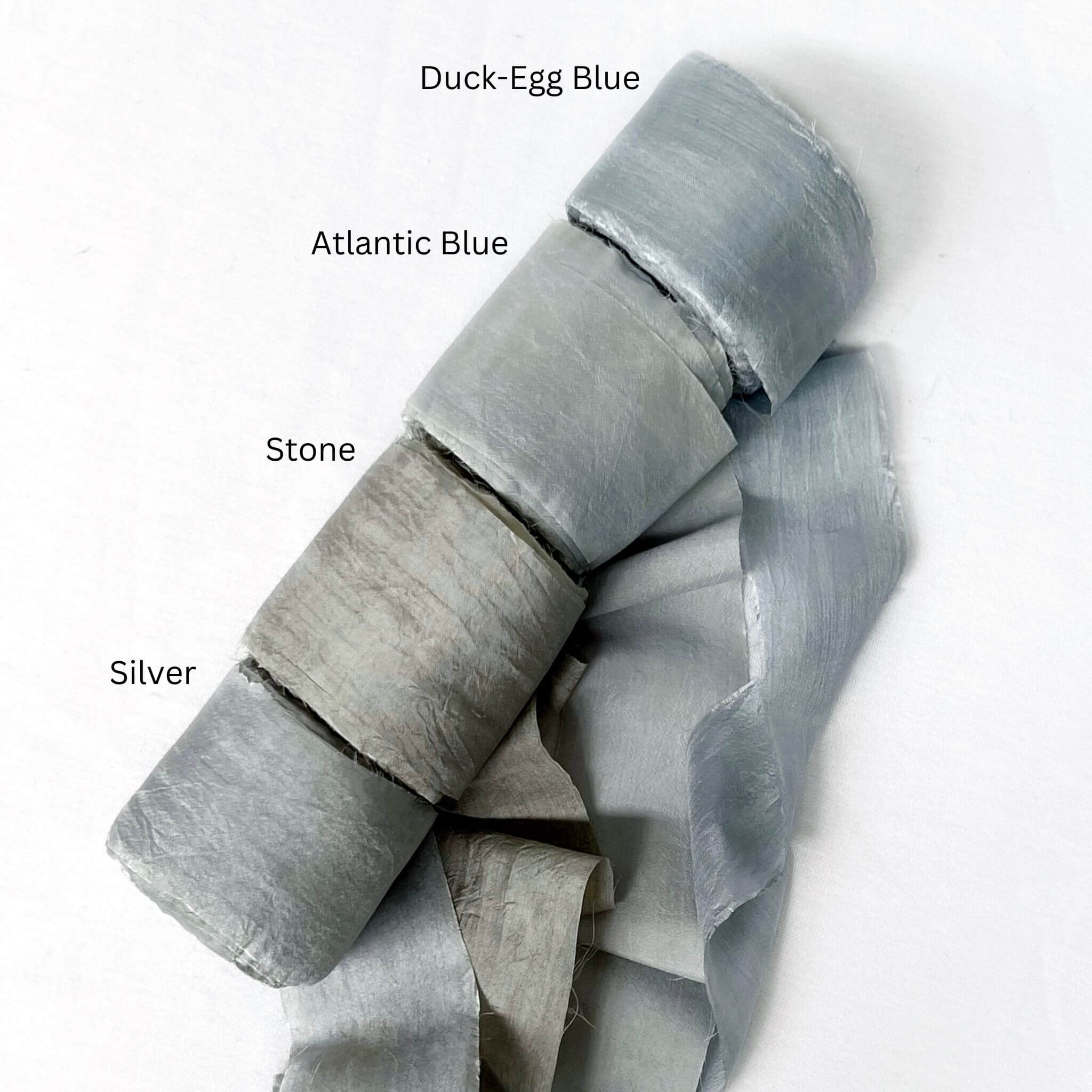 soft blue duck egg atlantic stone grey silver grey wide silk ribbon rolls for luxury gift wrapping on white wall