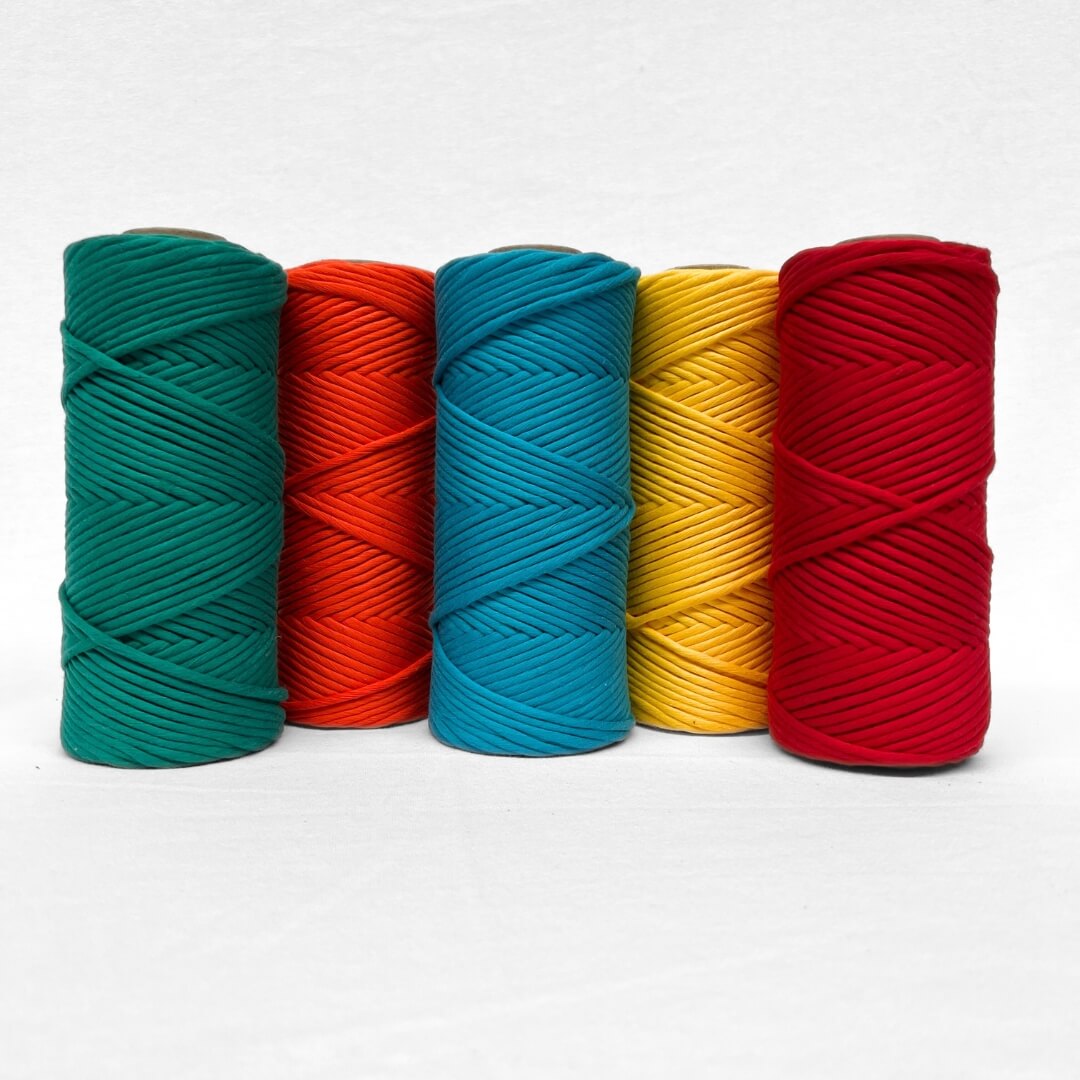 single roll of deep jewel green macrame cord laying flat on white wall