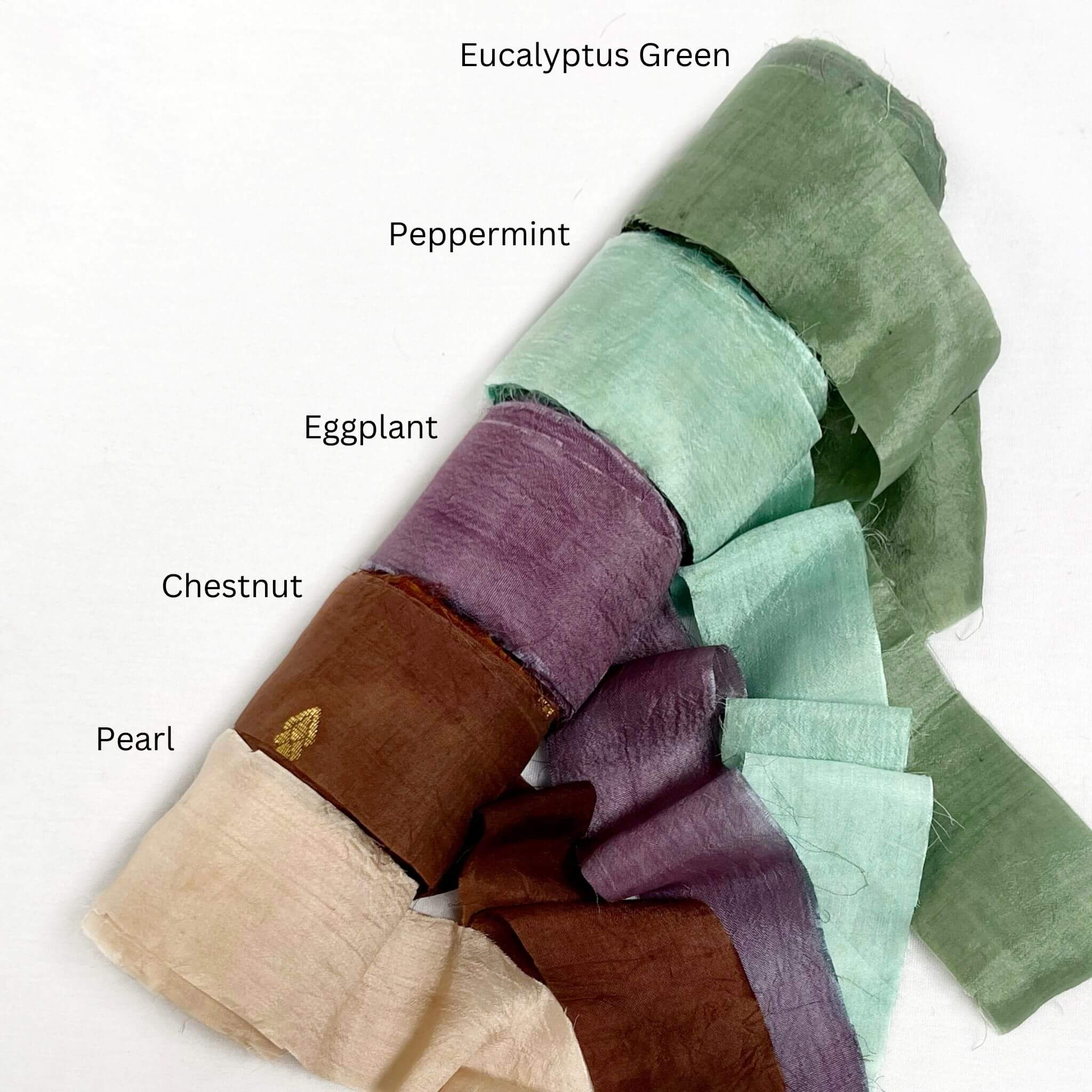 eucalyptus green peppermint green deep purple chestnut pearl group phoot og wide silk ribbon unravelled to show softness on white back ground