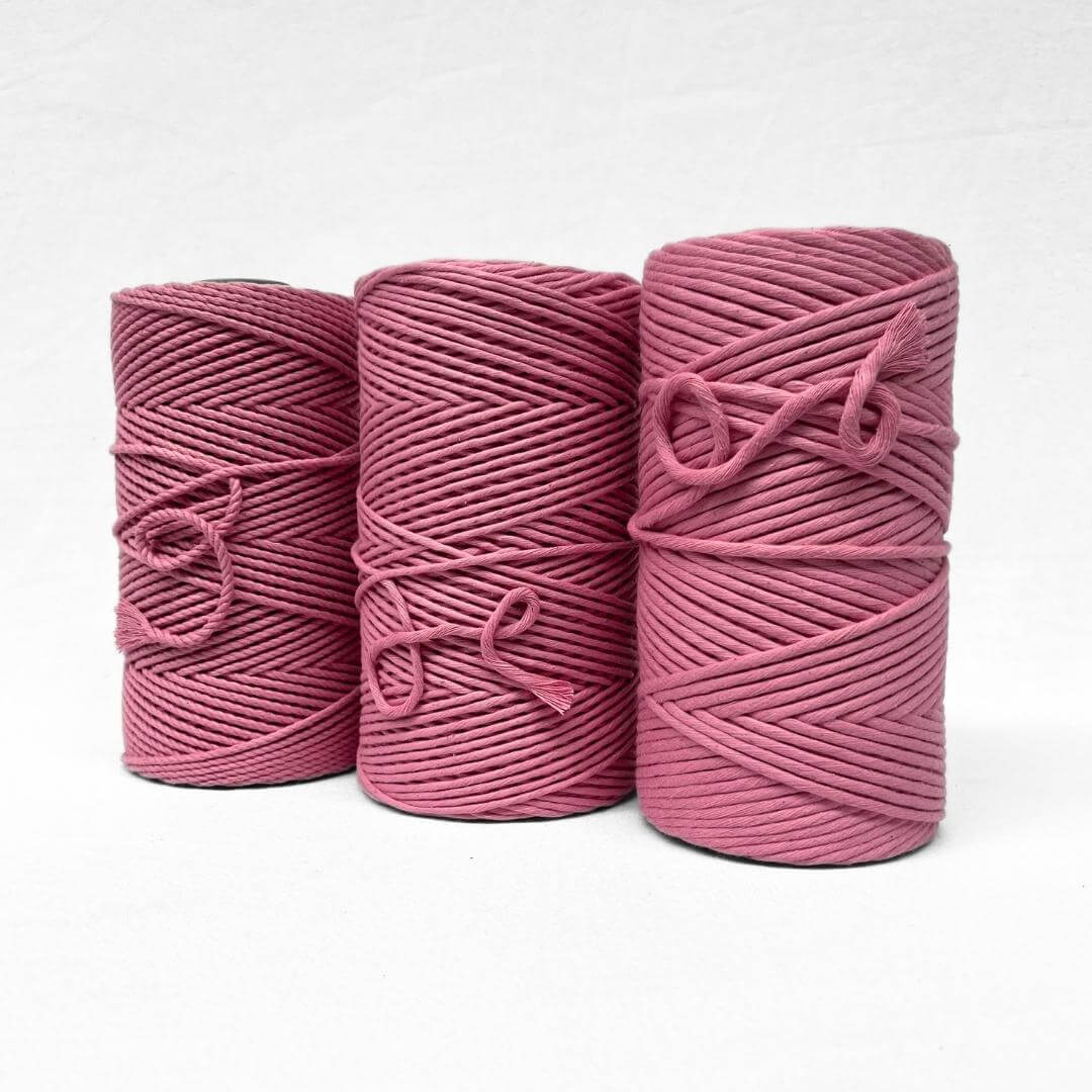 bright pink barbie pink cotton cord in image with single roll standing upright on white background