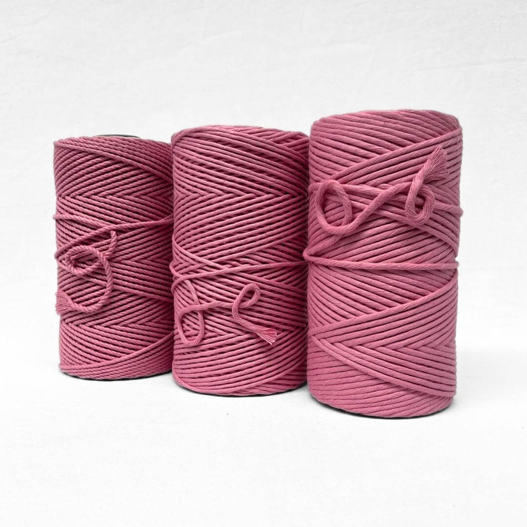 bright pink barbie pink cotton cord in image with single roll standing upright on white background 