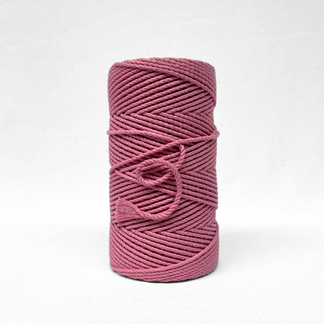 bright pink barbie pink cotton cord in image with single roll standing upright on white background