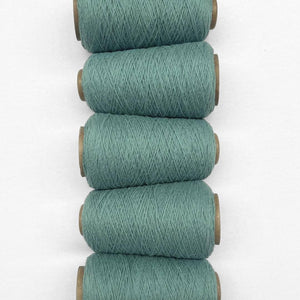 Five rolls of teal blue wool cord in flat lay image laying side by side on white background