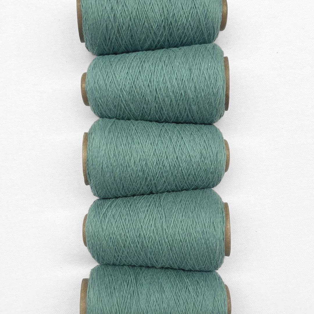 Five rolls of teal blue wool cord in flat lay image laying side by side on white background