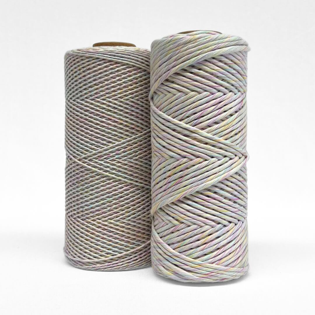 two rolls of rainbow mixed string standing upright on white background
