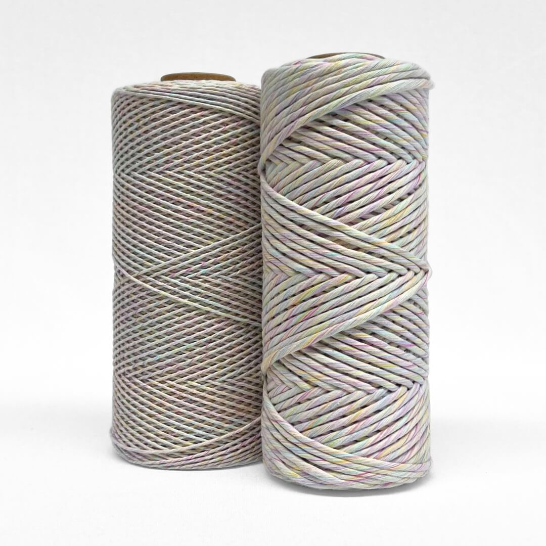 two rolls of rainbow mixed string standing upright on white background 