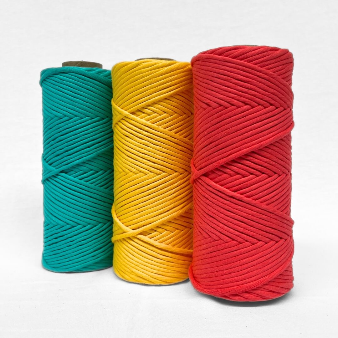 one rolls of cotton macrame cord in daffodil yellow laying flat on white background with small brushed out piece showing soft texture
