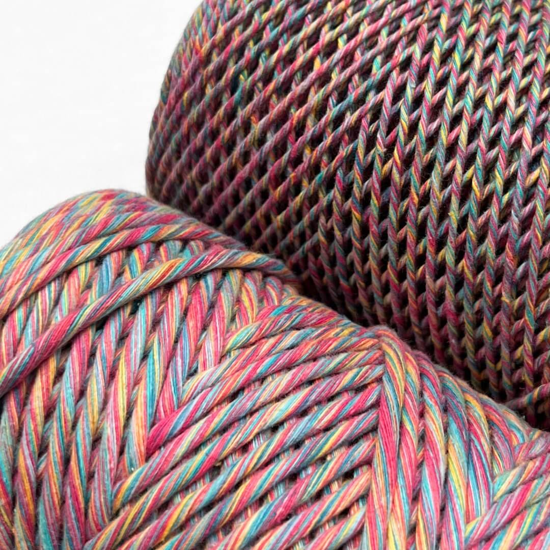 image of two rolls showing size variation of harlequin mixed macrame string colour way is blue pink purple yellow blue green 1.5mm and 4mm variation on white background