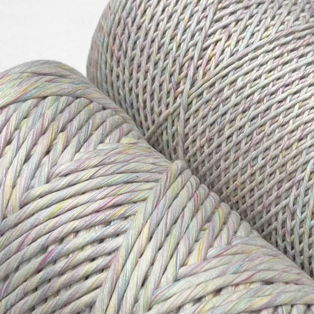 two rolls of rainbow mixed string standing upright on white background