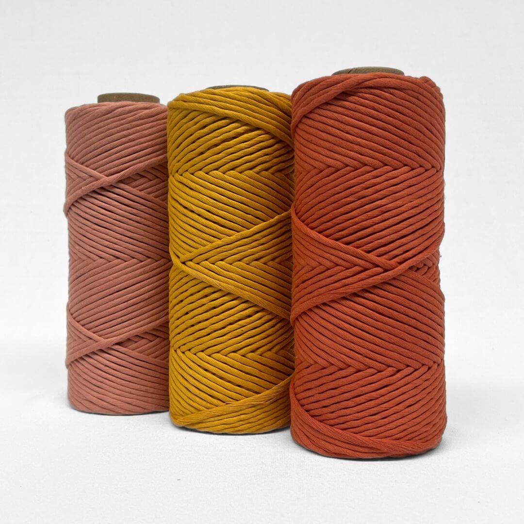 1a red earth macrame cord laying flat on white background wth small curled section showing softness