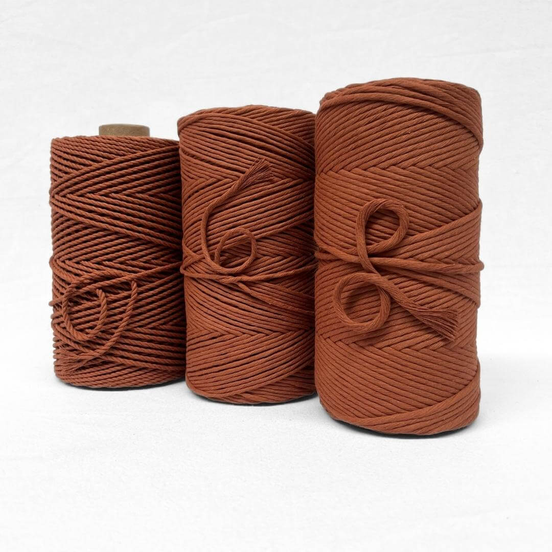 single roll of a red rust 4mm 3ply macrame cord in whtie background