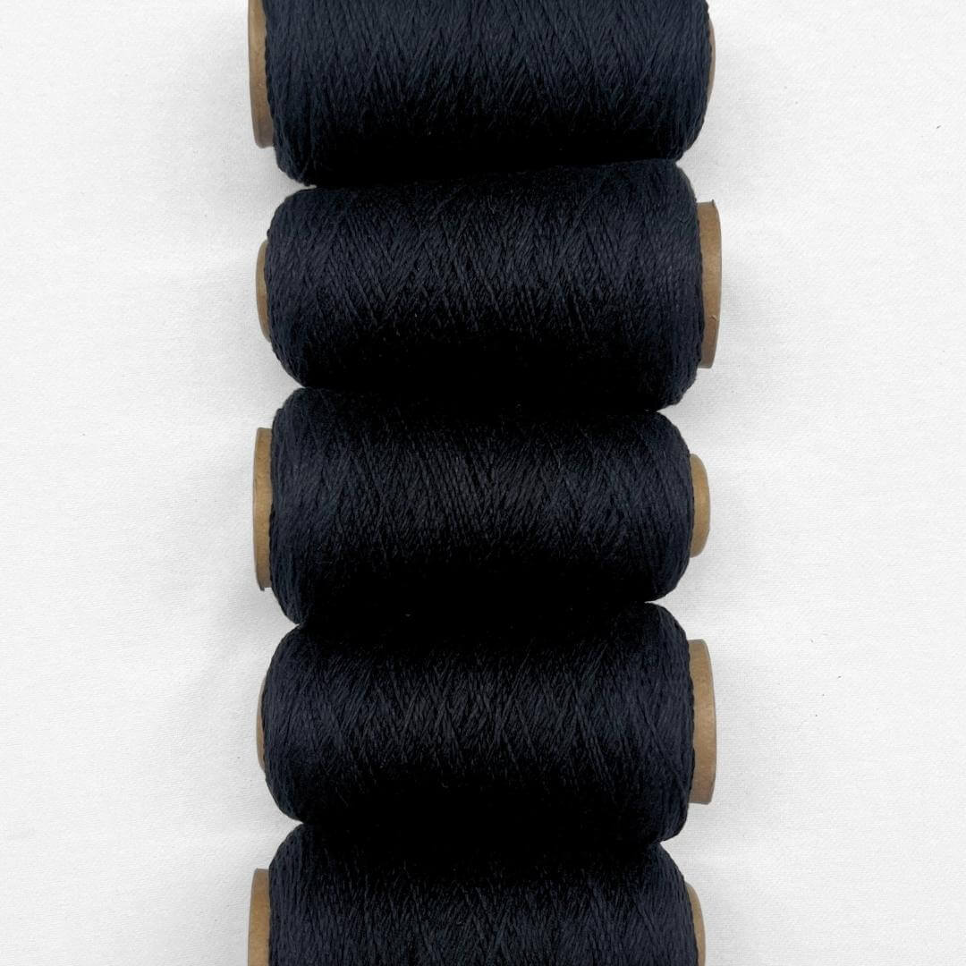 5 rolls of black wool rope laying side by side on white background