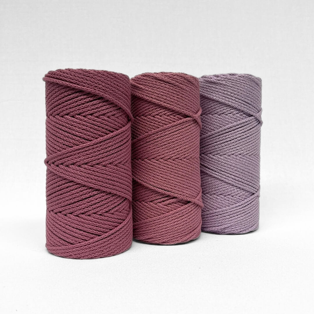 three rolls of 4mm braided rope in colours plum pink primrose pink and orchid standing on angle with white background