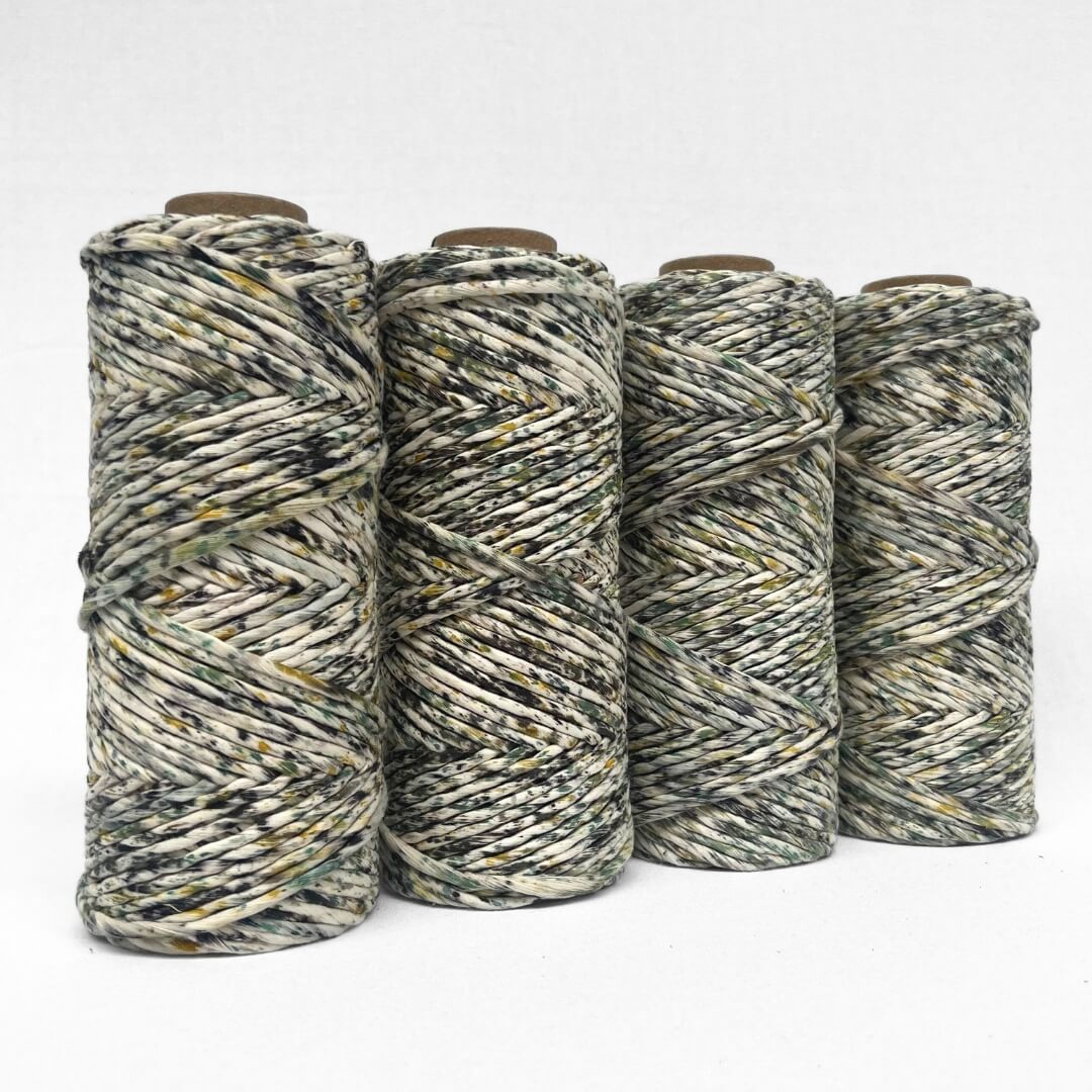 yellow green and black speckled macrame cord four rolls standing side by side on white background