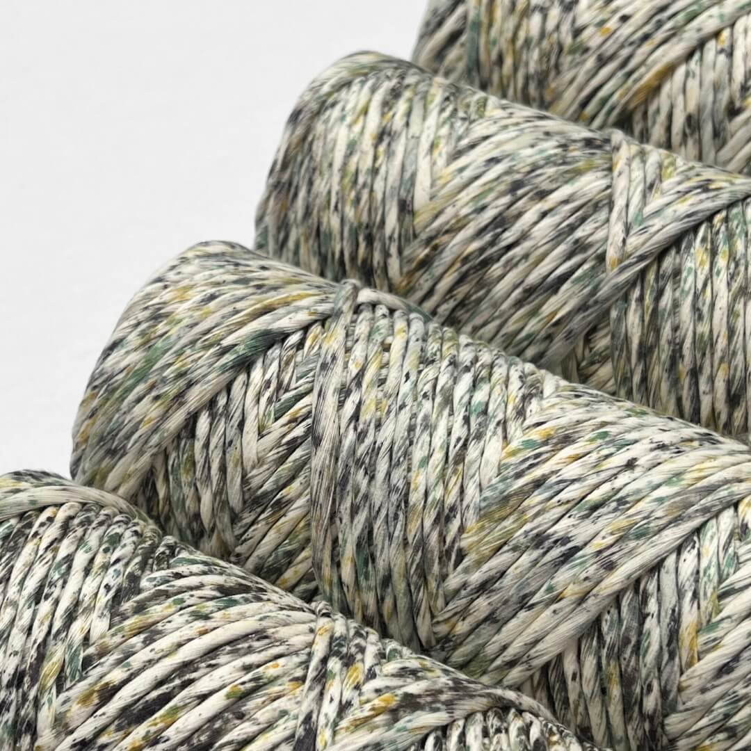 yellow green and black speckled macrame cord four rolls standing side by side on white background