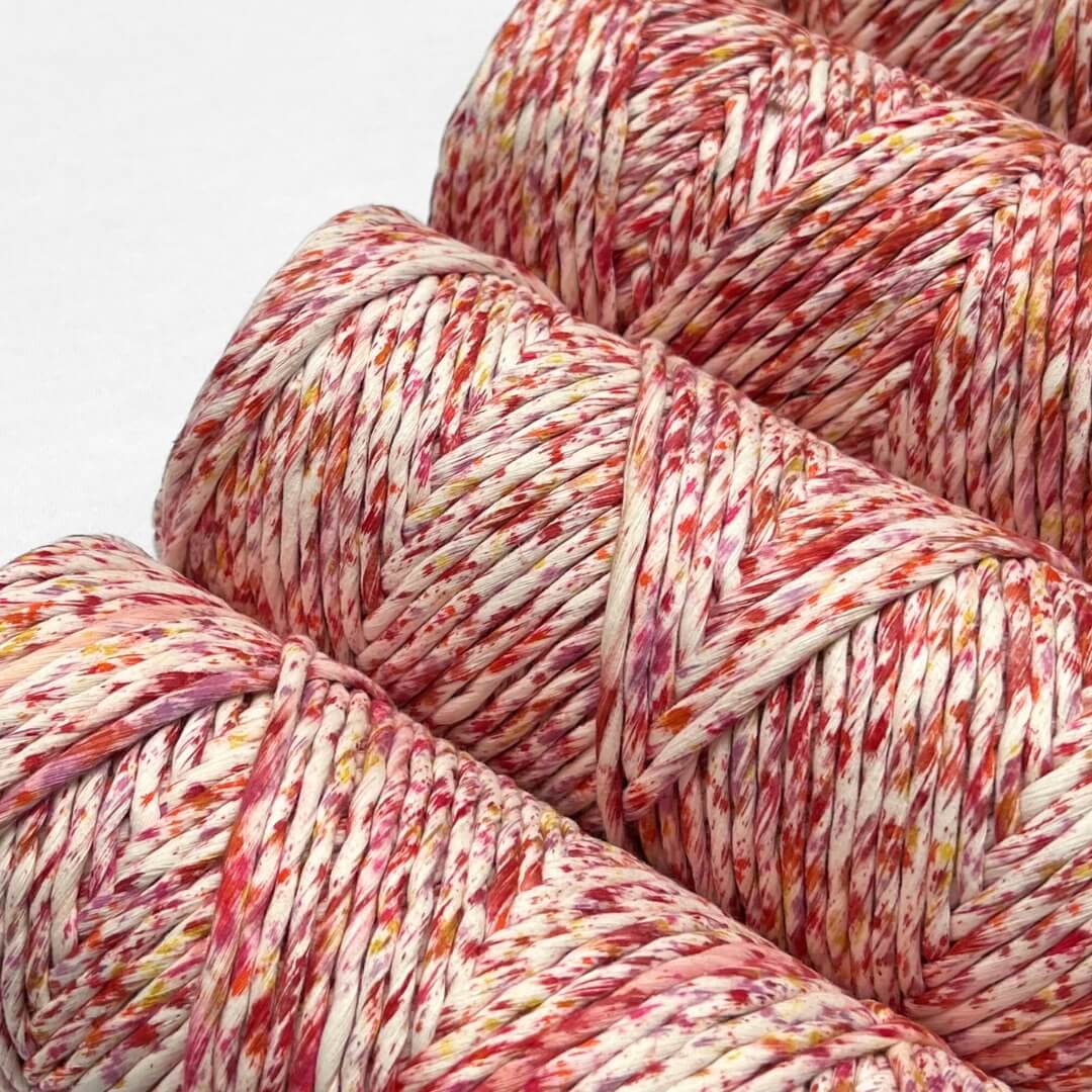 combination photo showing four rolls of vibrant red yellow and orange confetti cotton cord standing upright on white background