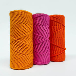 three rolls of neon coloured macrame cord in white background