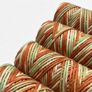 four rolls of Banksia hand painted string laying flat on white background showing up close colour melt