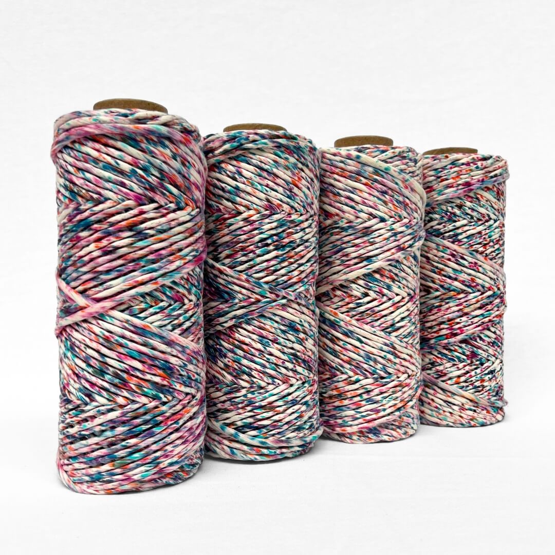 four rolls of harlequin confetti cotton string pink orange blue bold colour melt standing side by side on white background