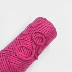 single roll of hot pink macrame cord on white background
