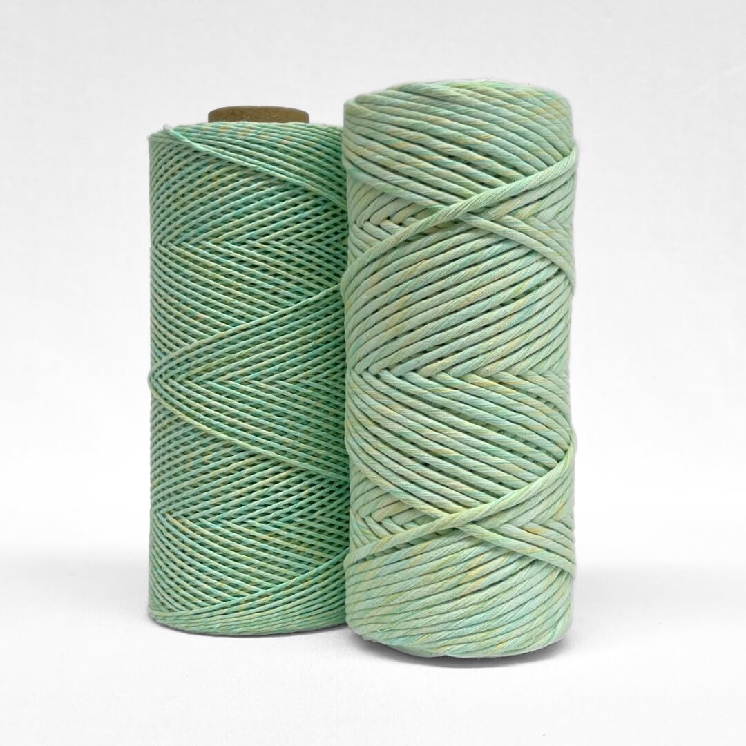 two rolls of lime splice cotton macrame ixed string standing sie by side on white background in 4mm and 1.5mm variants