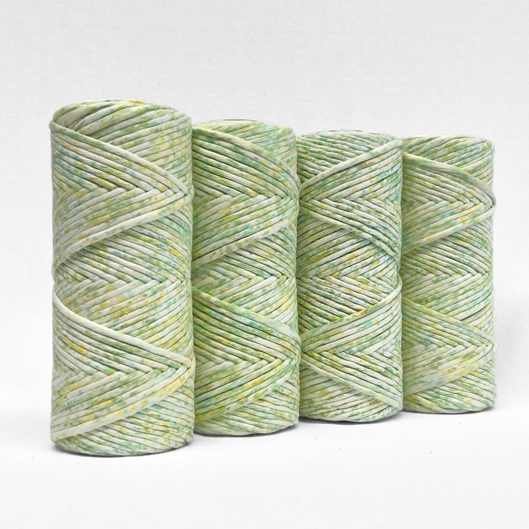 four rolls of lime splice watercolour macrame string standing upright on white background 