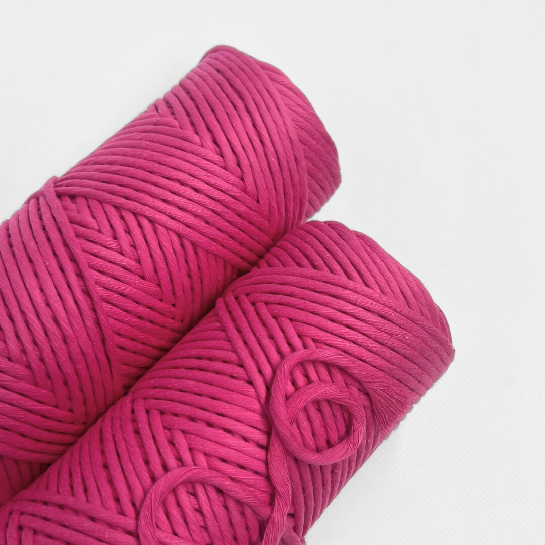single roll of hot pink macrame cord on white background