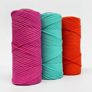 three rolls of neon cord in pink, blue and orange on white background