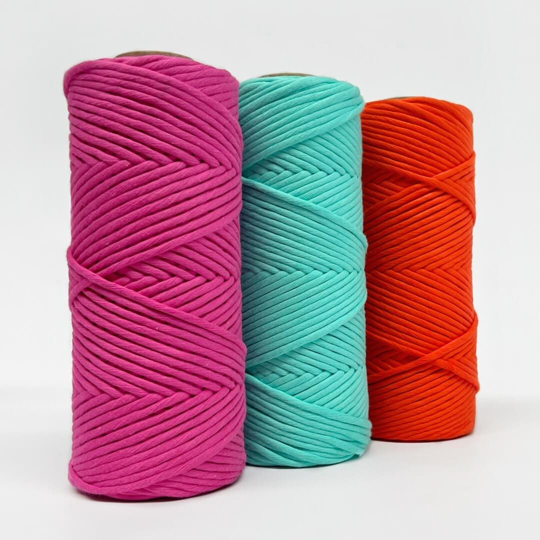 three rolls of neon cord in pink, blue and orange on white background