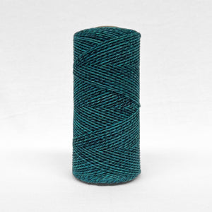 single roll of vibrant blue and black mixed cotton cord in 1.5mm standing alone on white back drop