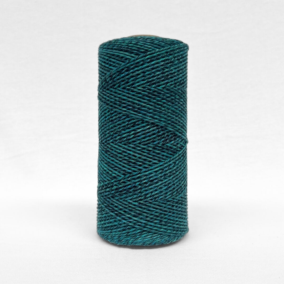 single roll of vibrant blue and black mixed cotton cord in 1.5mm standing alone on white back drop
