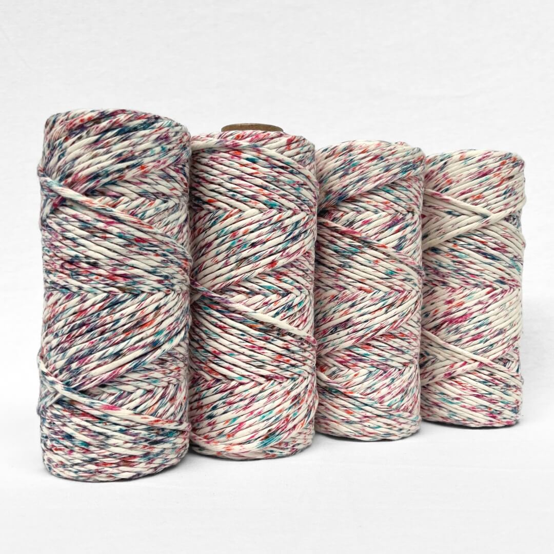 four rolls of harlequin confetti cotton string pink orange blue bold colour melt standing side by side on white background
