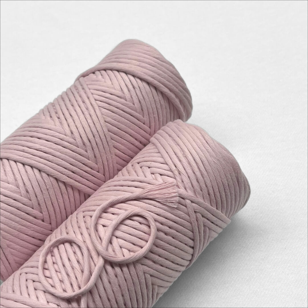 two rolls of macrame cord in muted pink colourway laying flat on white background