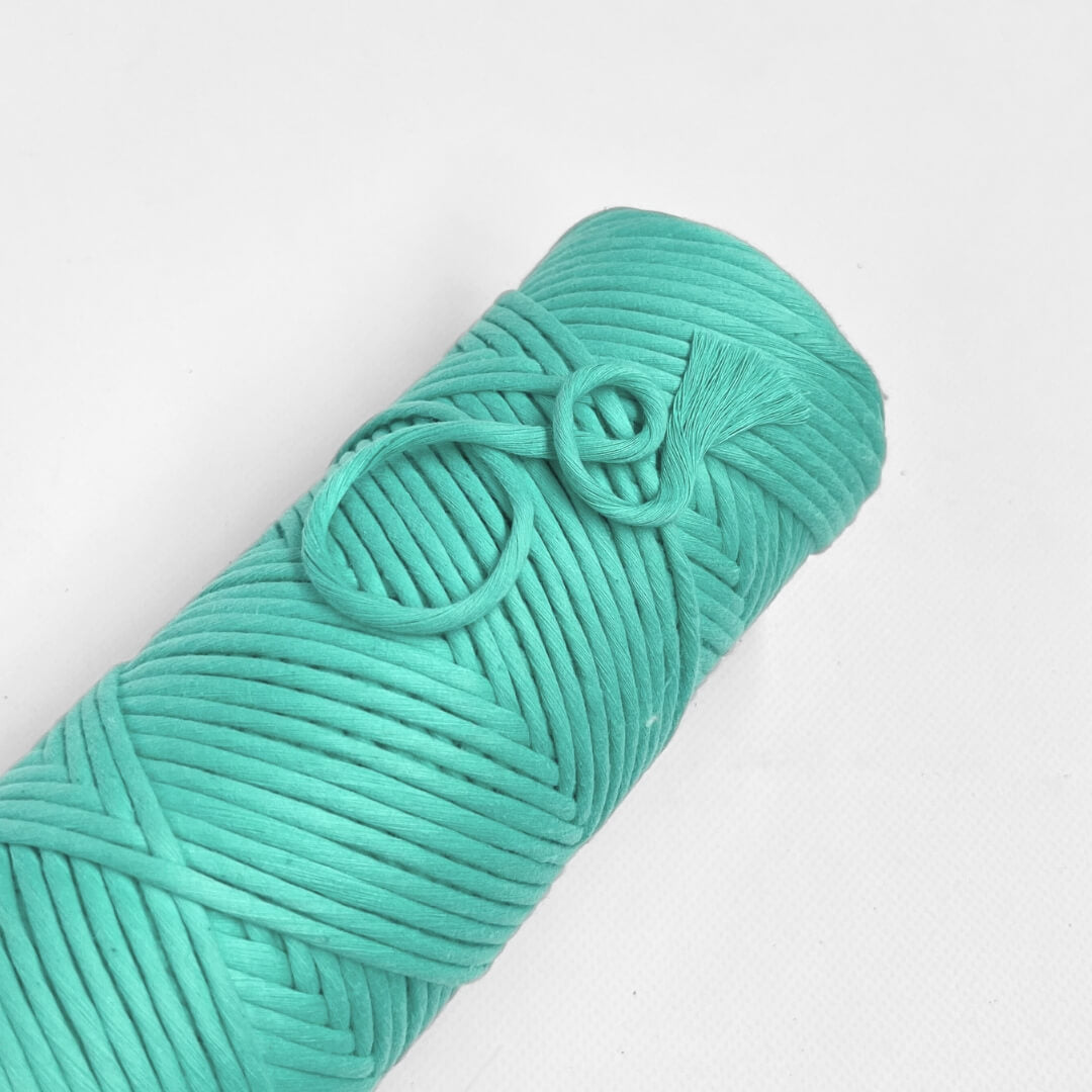 one roll of neon blue cotton macrame string macrame cord laying flat on white background