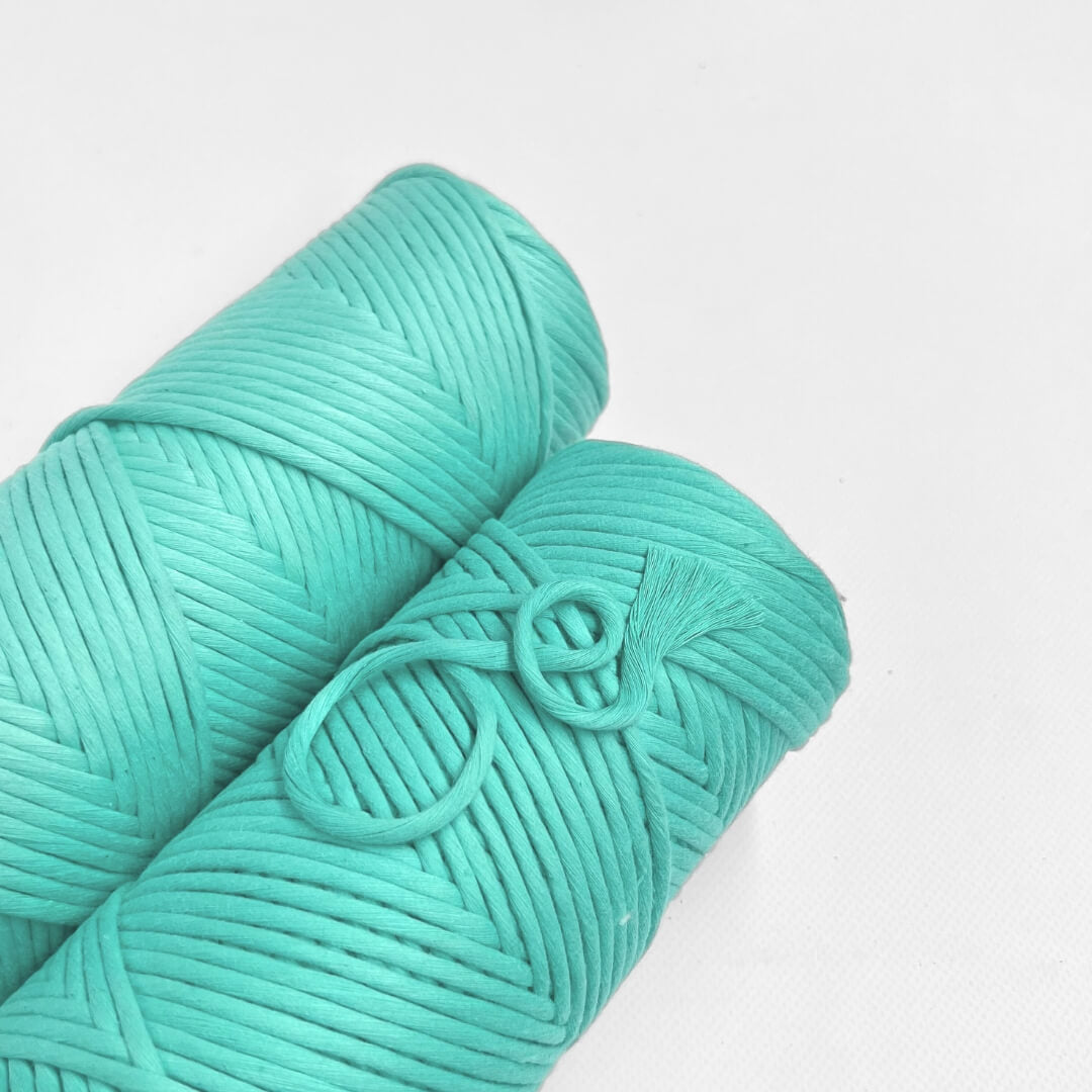 one roll of neon blue cotton macrame string macrame cord laying flat on white background