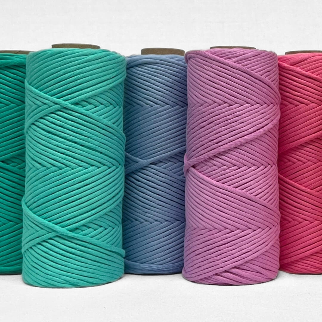 one roll of vivid violet macrame cord laying flat on white background