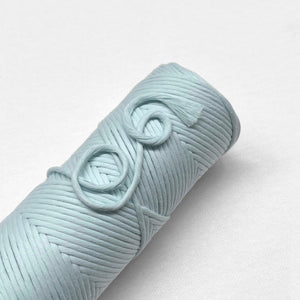 one roll of cototn amcrame cord in pastel blue colour laying flat on white background