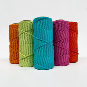five rolls of neon macrame string on white background showing orange, red, green, blue, pink and red colours