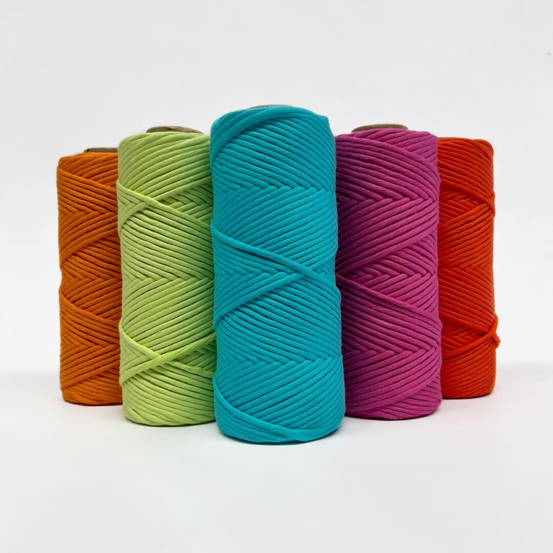 five rolls of neon macrame string on white background showing orange, red, green, blue, pink and red colours