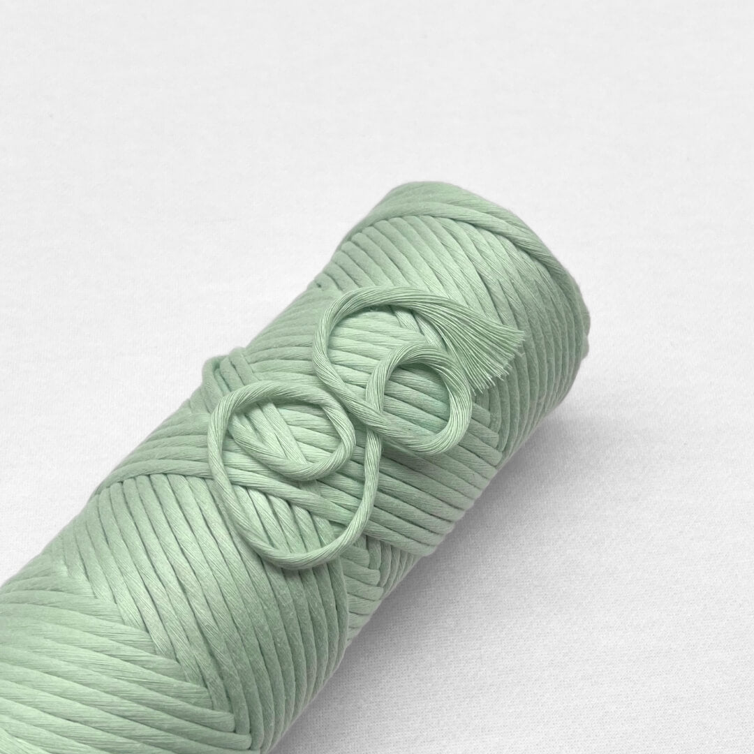 single rolls of mint green amcrame cord laying on white background
