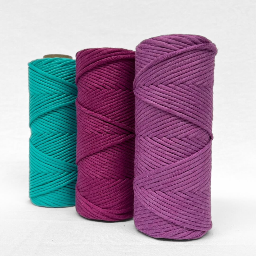 one roll of macrame cotton string laying angled and flat in colour royal purple on white background