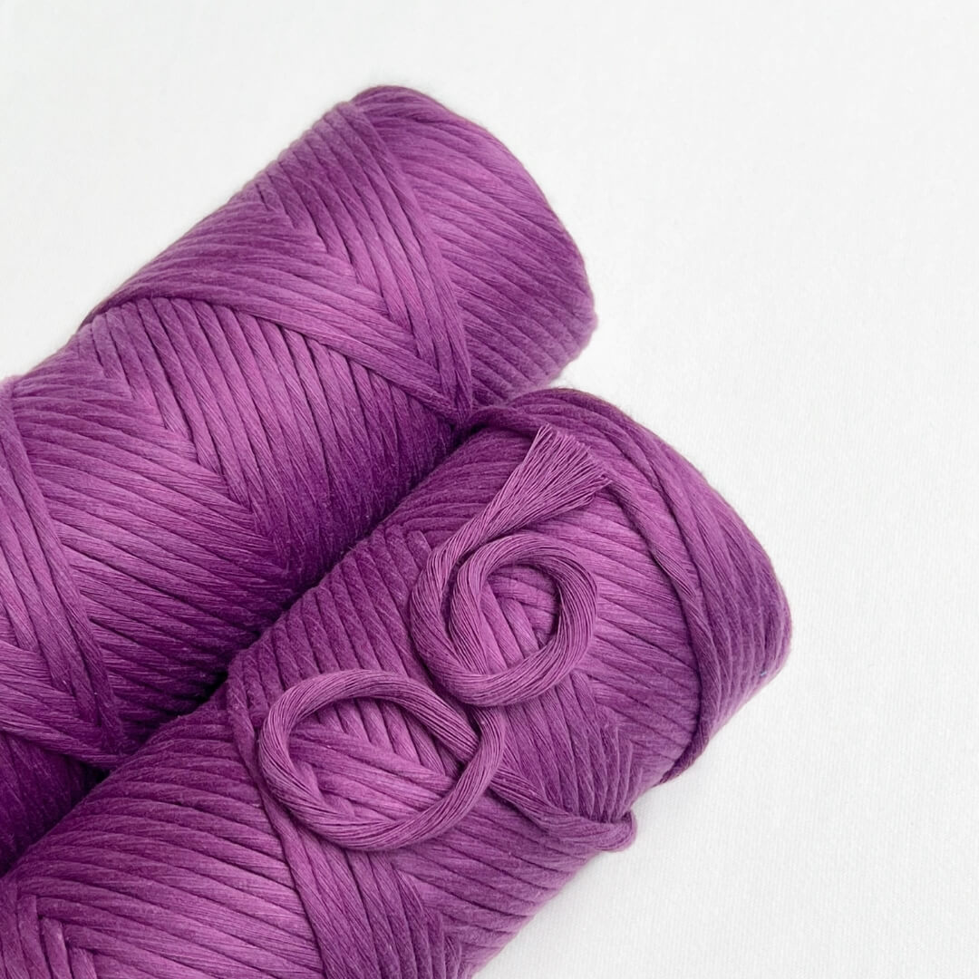 two rolls of royal purple preium cord laying falat on white back drop small brushed out peice demonstrating softness of cord