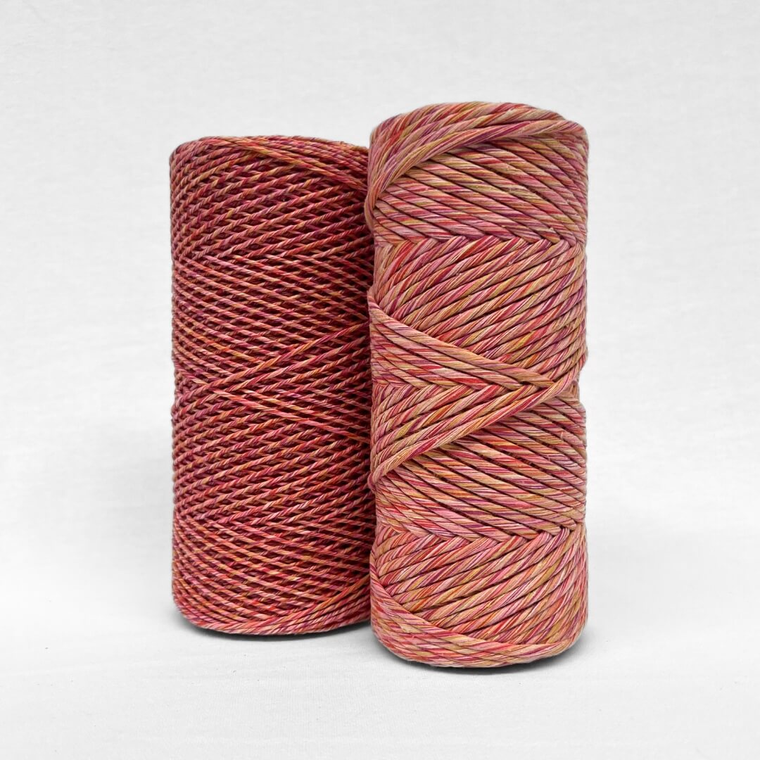 orange pink purple and yellow colour way of mixed string stnading side by side on white wall