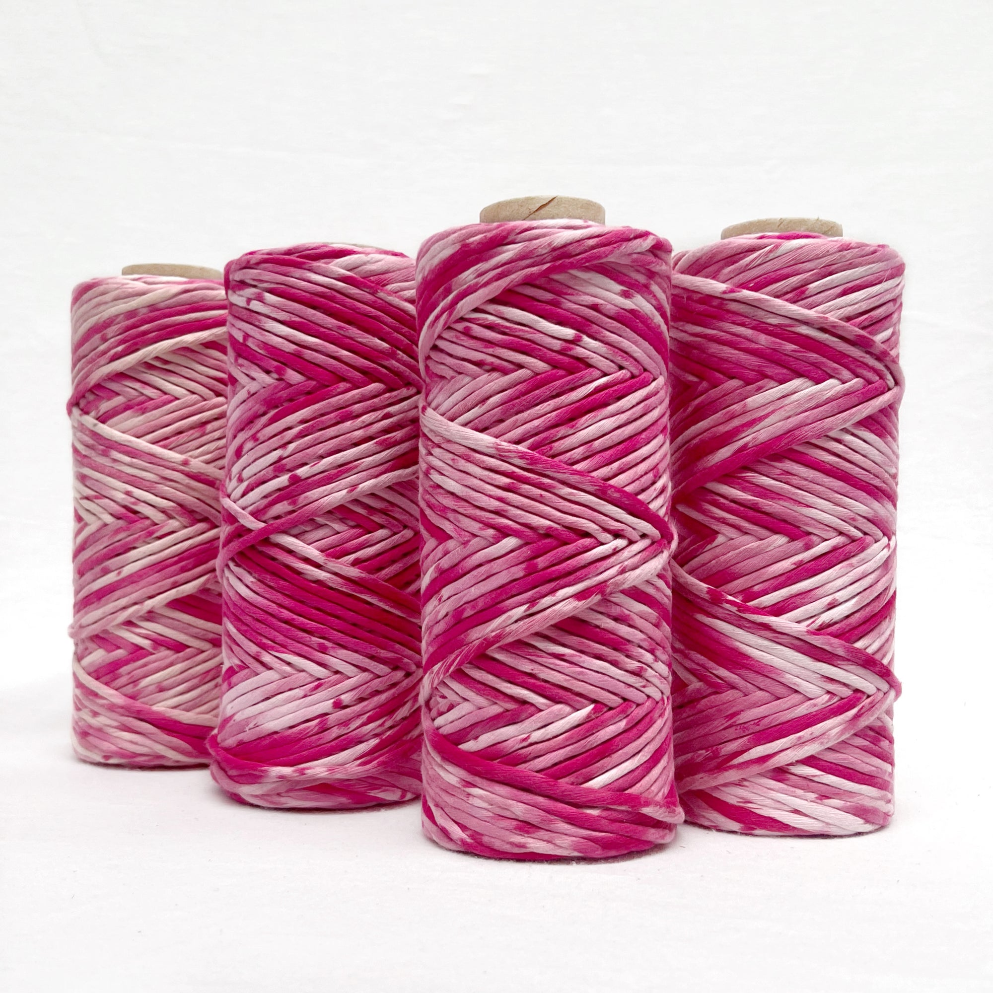 bright pink macrame cord standing in line against white wall