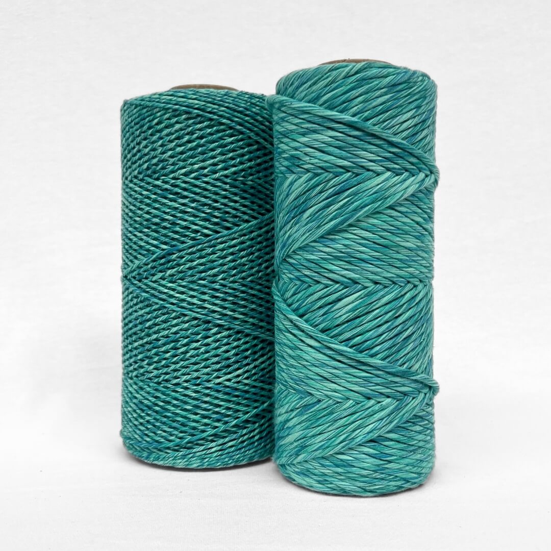 two rolls of blue and green multicoloured string called blue lagoon standing upright on white background