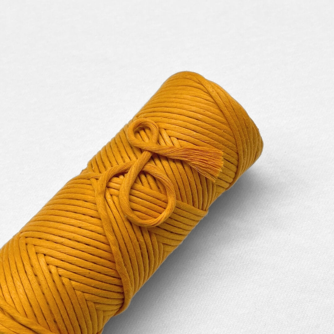 single roll of mellow marigold 4mm cotton string lying flat on white background