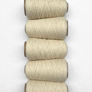 Five cones of natural thin wool yarn laying in flat lay side-by-side vertically on white background