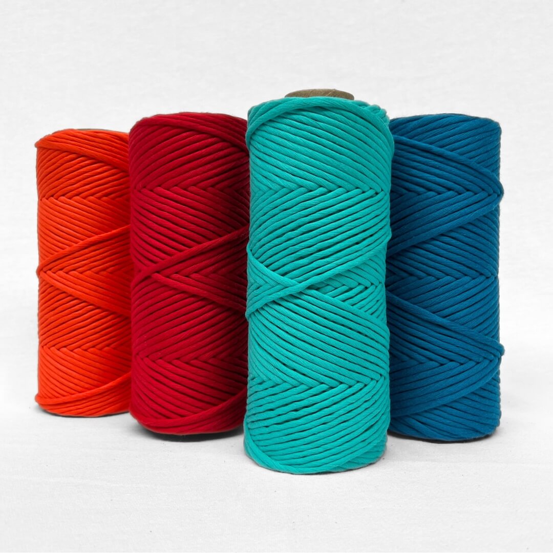 combination image showing four rolls of cotton cord for macrame and diy in vibrant complementing colours flame orange ladybug red turquoise blue and mykonos blue standing on white wall